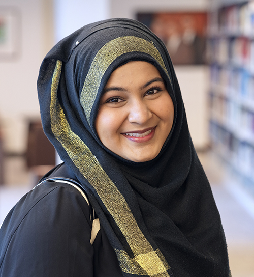 Professional headshot of Noor in a library setting.