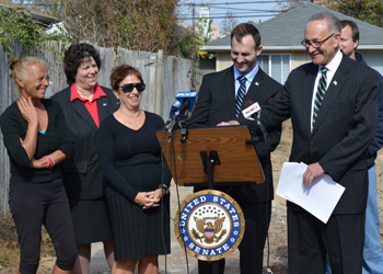 Touro Law Professor Benjamin Rajotte, Director of the Disaster Relief Clinic, at the podium next to Sen. Schumer with Dean Patricia Salkin (second from left) and victims of Superstorm Sandy at a press conference on October 22, 2013.